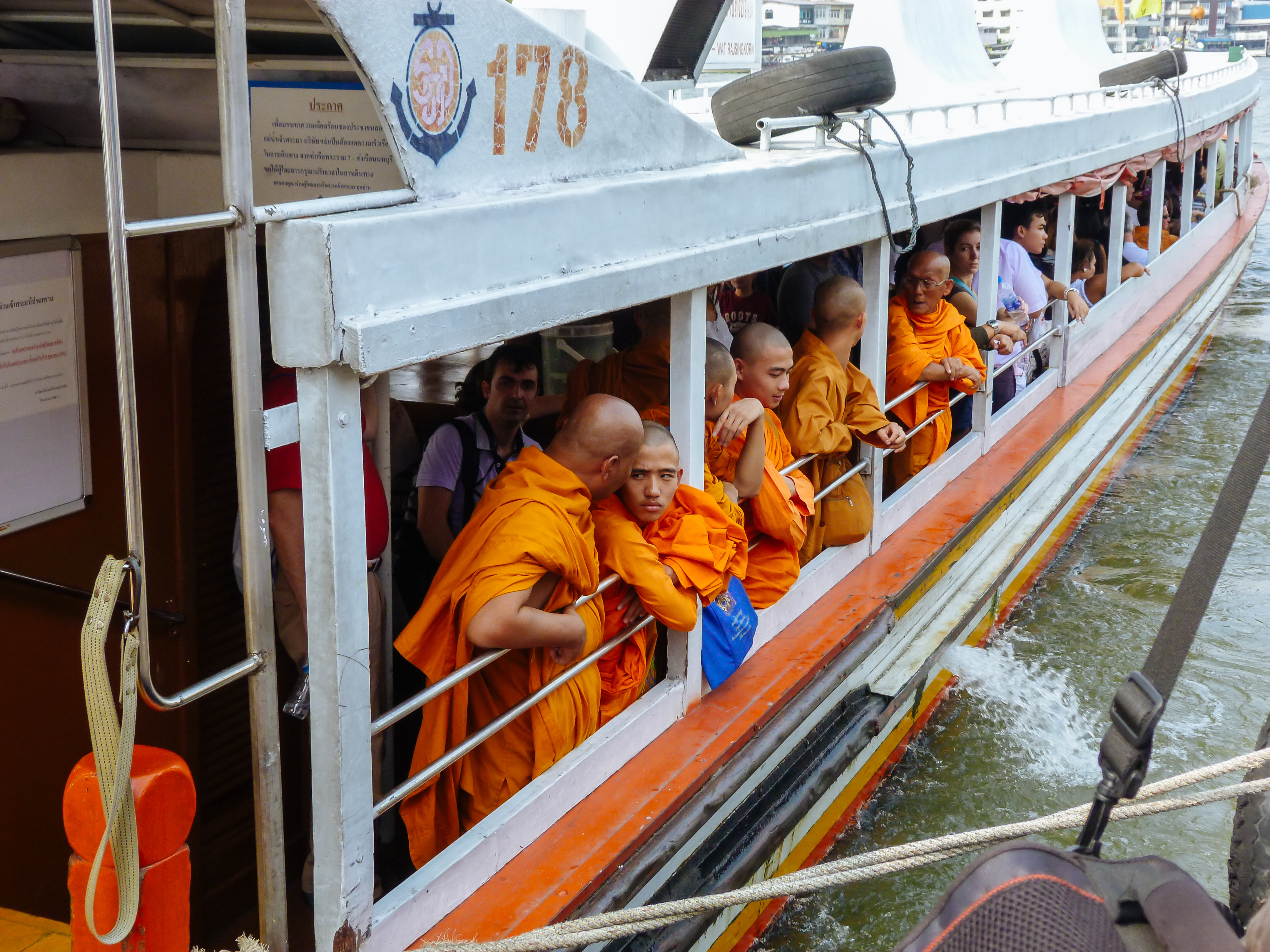 Chao Phraya Express Boat mit orangefarbener Flagge, Wat Arun im goldenen Abendlicht