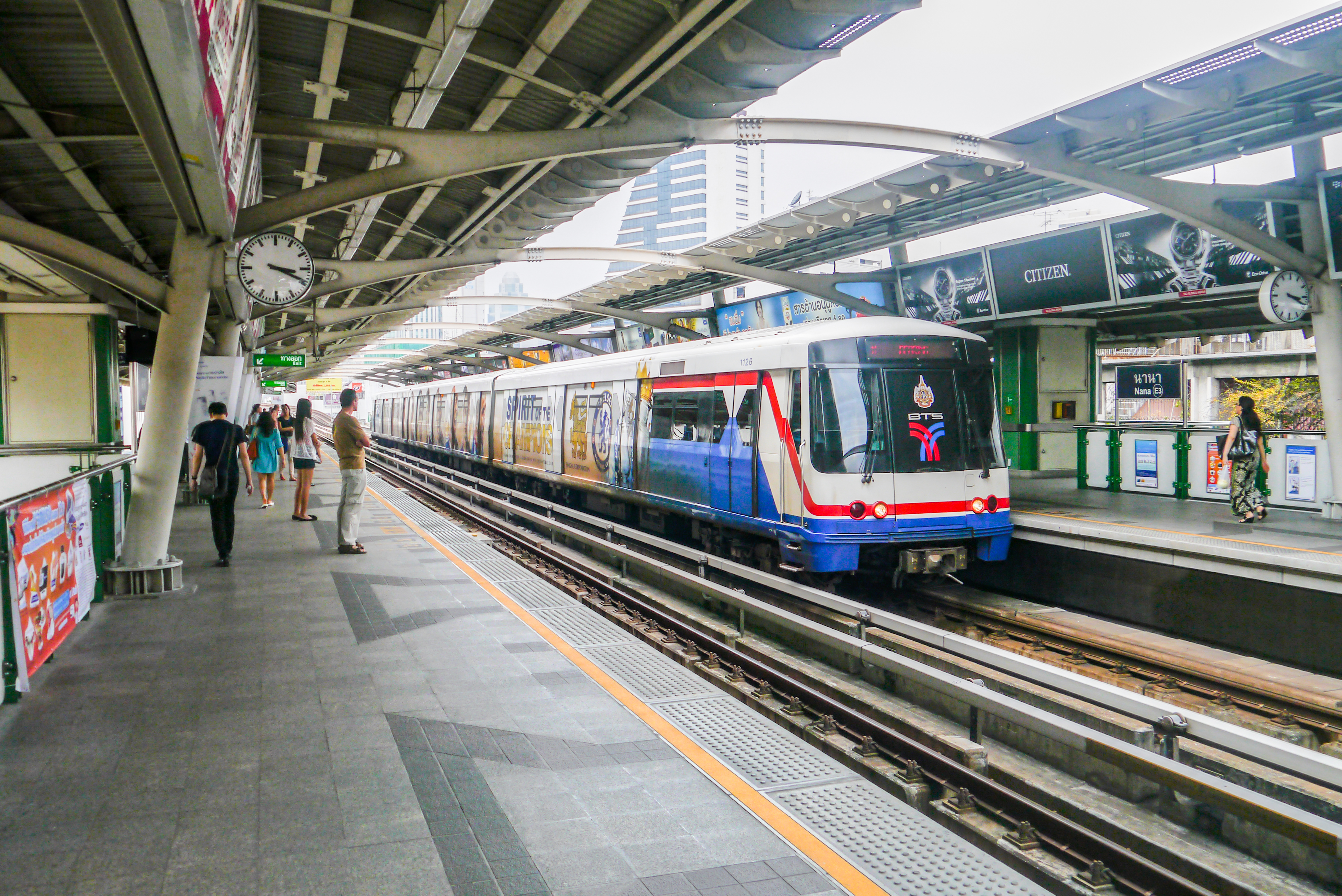 BTS Skytrain-Zug an Bangkoker Hochbahnstation mit Skyline im Hintergrund
