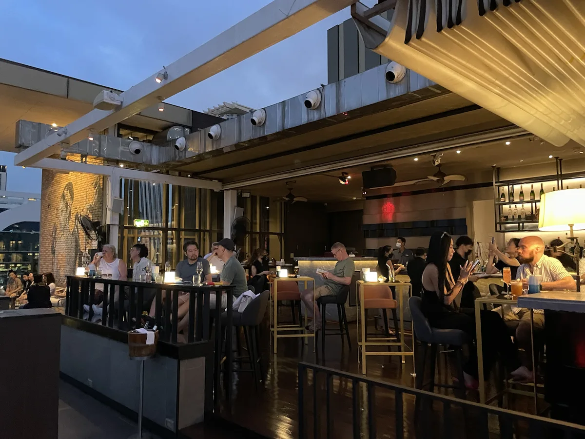 Hotel Indigo Bangkok – Rooftop-Bar am Abend, belebt