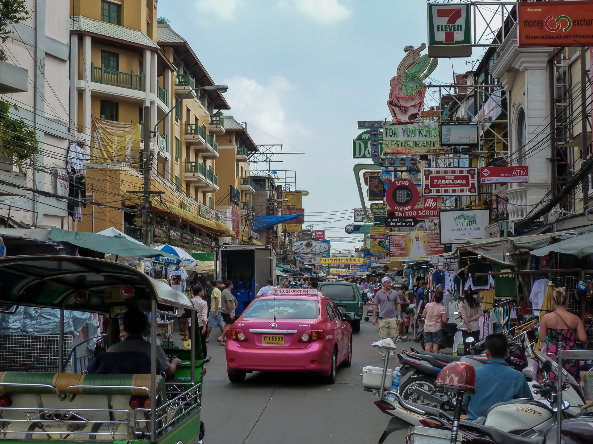Khao San Road in Bangkok mit Tuk Tuk, 7-Eleven-Schildern und Straßenleben