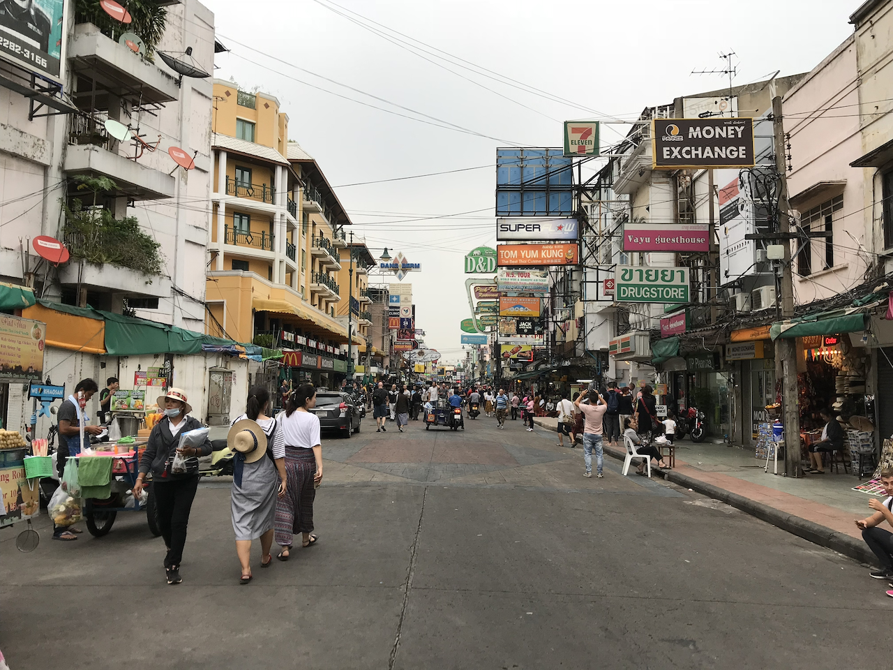 Khao San Road in Bangkok mit Reisebüros, Straßenschildern und Fußgängern
