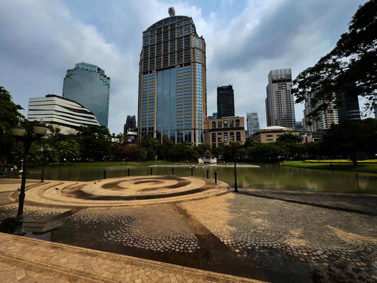 Benjasiri Park nahe Thonglor mit Teich, Mosaik-Spirale und Bangkoks Hochhaus-Skyline im Hintergrund