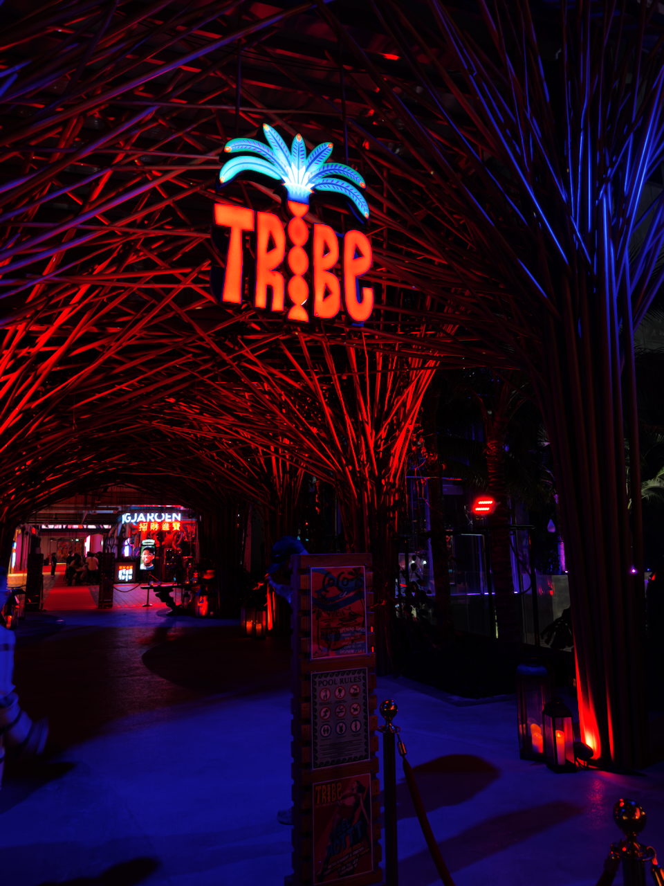 TRIBE Club Eingangsbereich in Thonglor – rote Bambus-Lichtinstallation mit TRIBE-Leuchtschild und Palmen-Logo