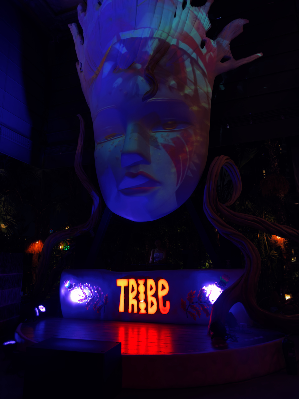 TRIBE Club Thonglor – erleuchtete riesige Frauenskulptur mit blauem Projektionslicht und tropischen Pflanzen