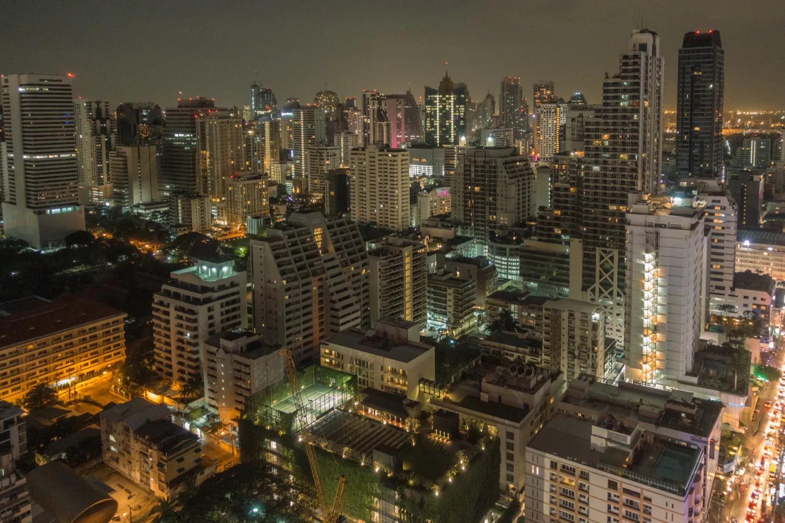 Nächtliche Skyline von Bangkok mit beleuchteten Hochhäusern vom Rooftop aus gesehen