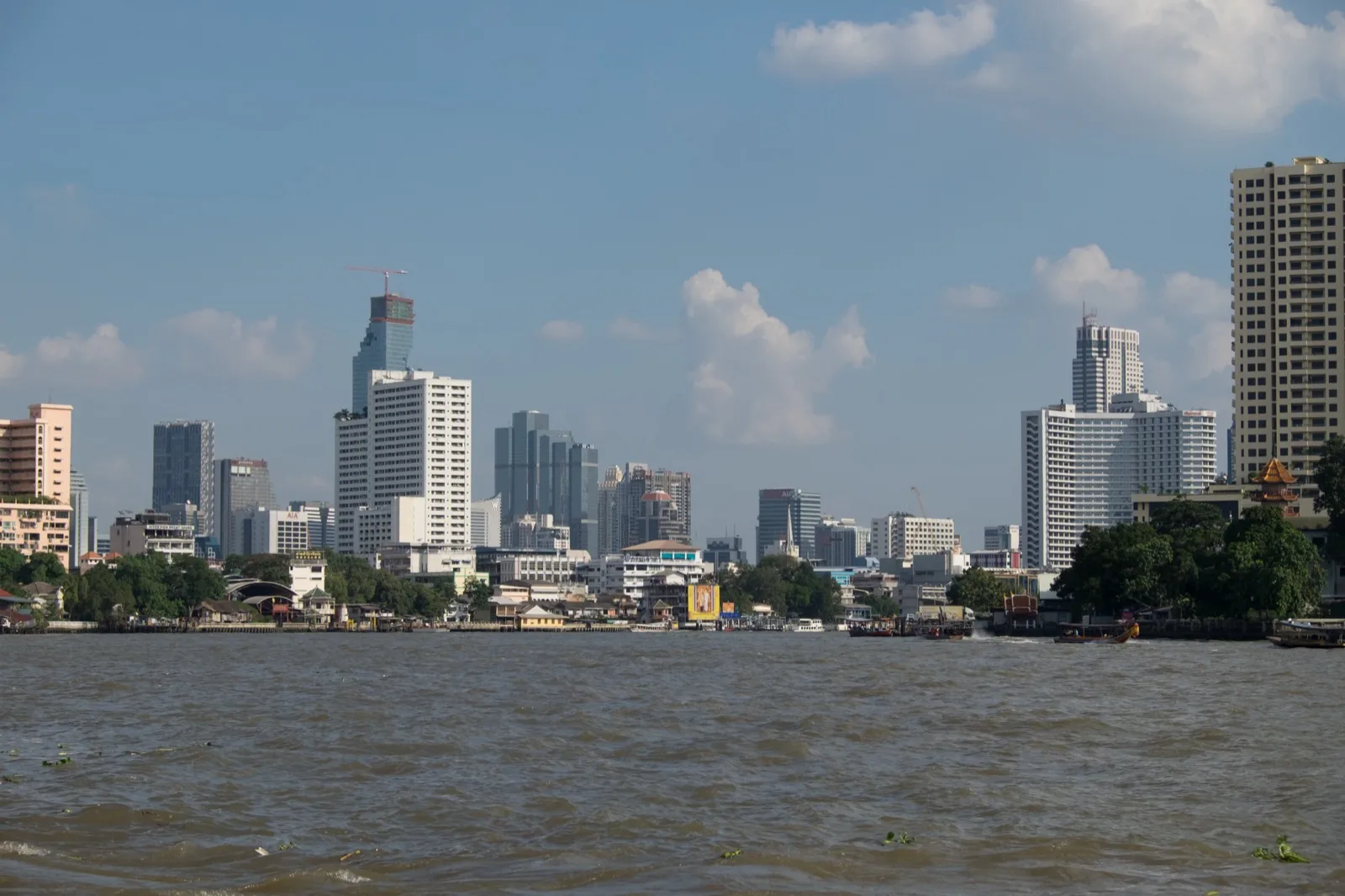 Blick vom Chao Phraya auf das Flussufer und die Skyline von Bangkok