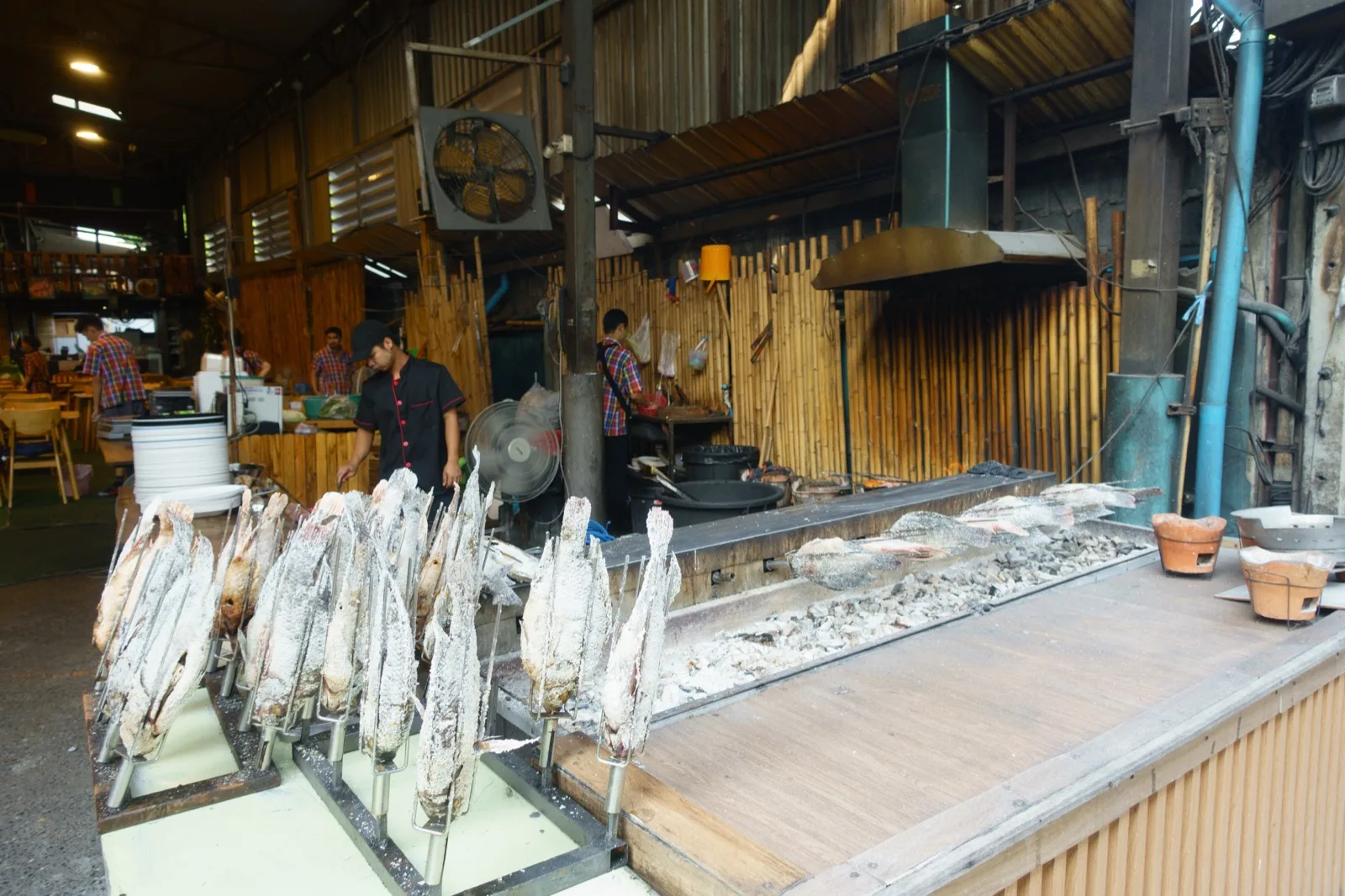 Salzkrusten-Fisch am Grill einer Garküche auf einem Markt in Bangkok