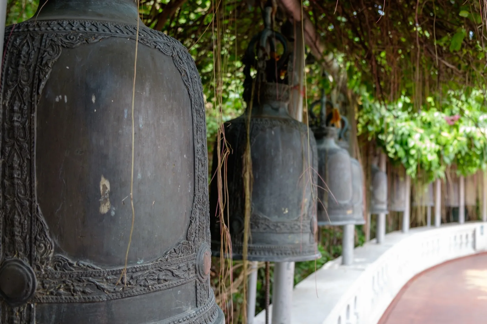 Reihe alter Bronzeglocken entlang des Aufstiegswegs am Wat Saket in Bangkok