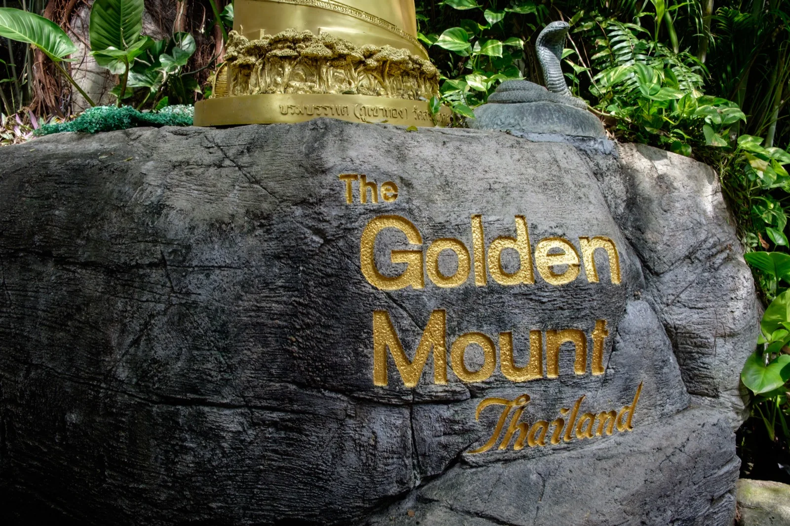 In Stein gemeißelter goldener Schriftzug The Golden Mount am Fuß des Wat Saket in Bangkok