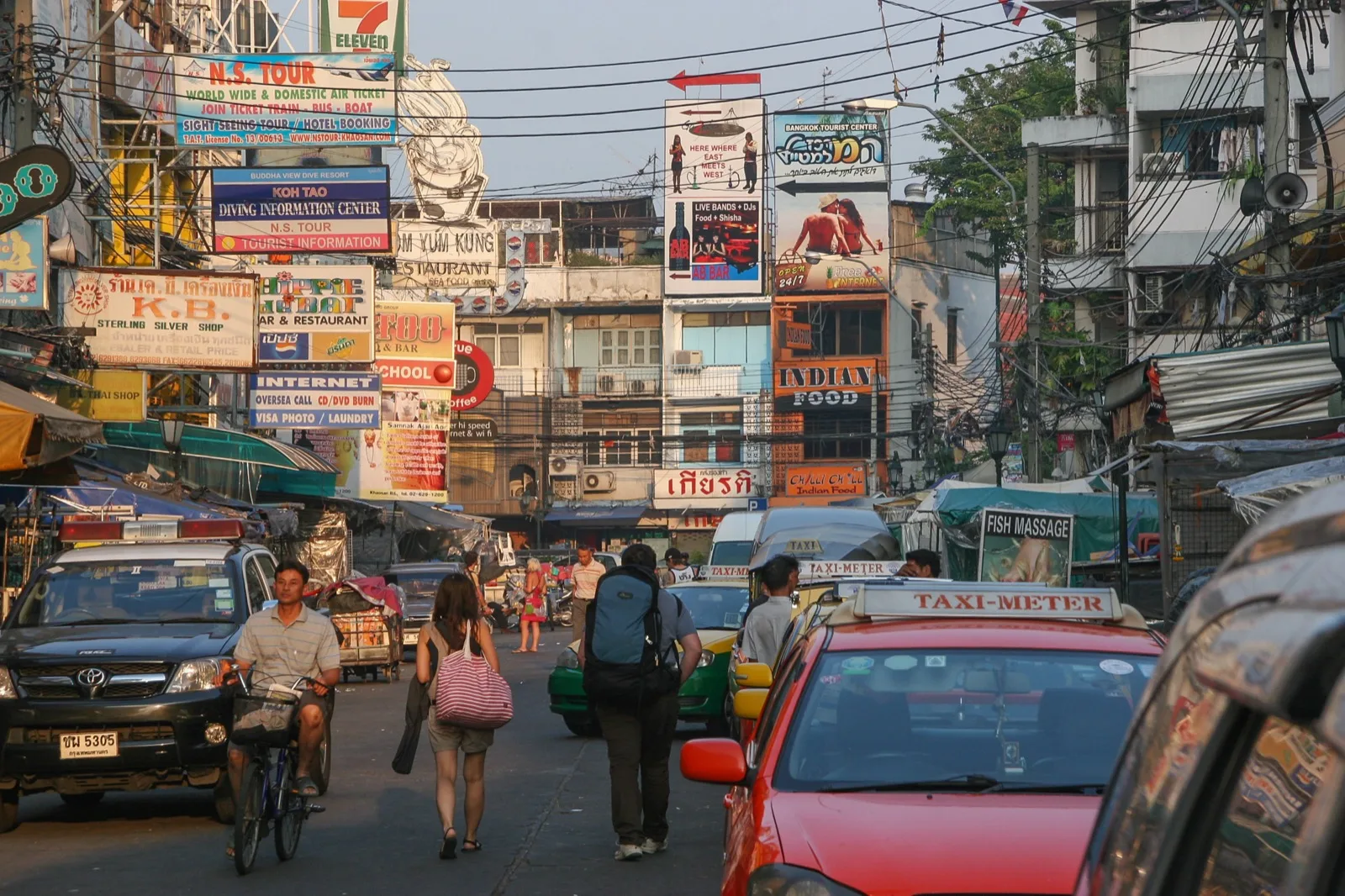 Straßenszene auf der Khao San Road in Bangkok mit Schildern, Taxis und Fußgängern