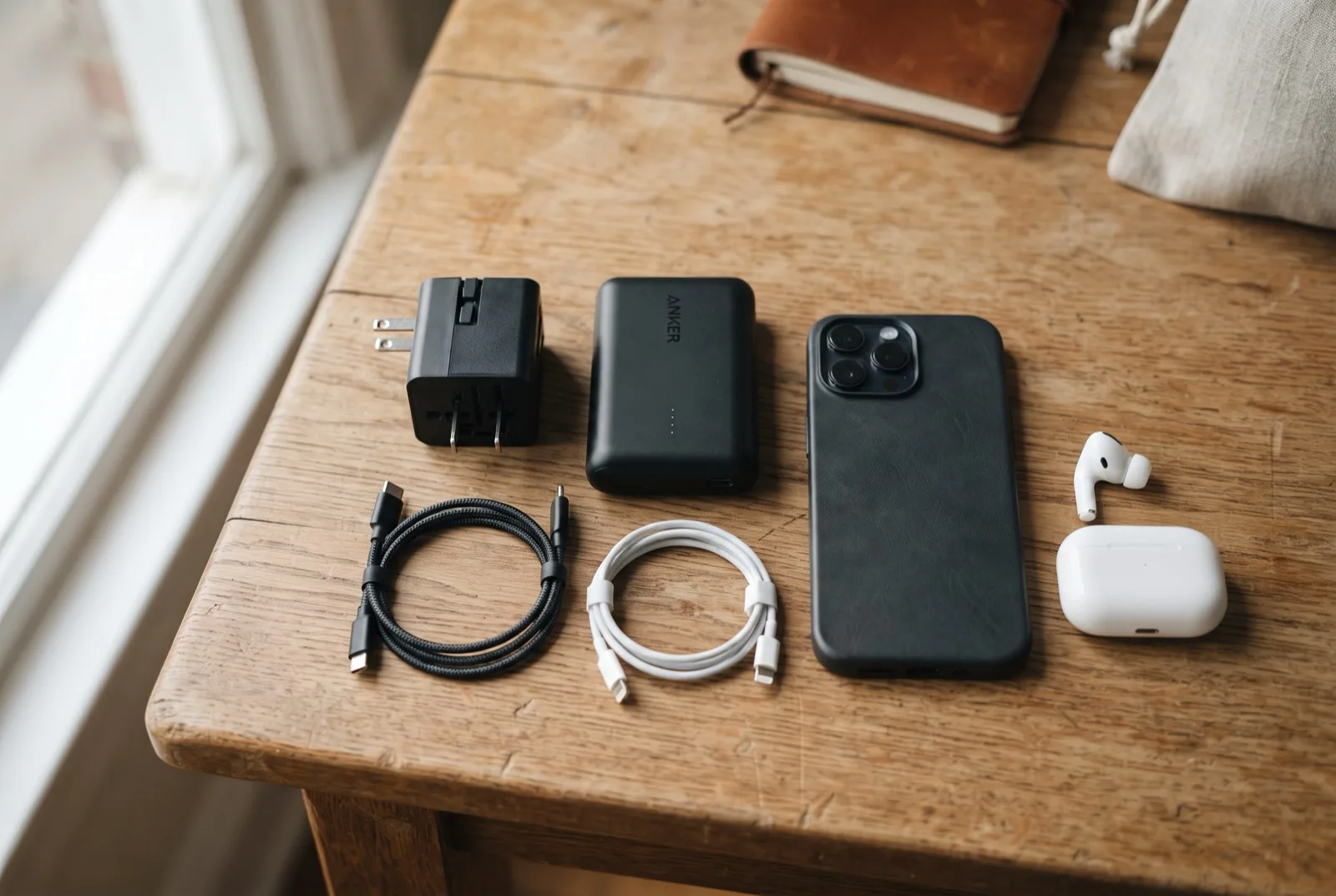 Reiseadapter, Powerbank, Kabel und Smartphone auf einem Holztisch arrangiert