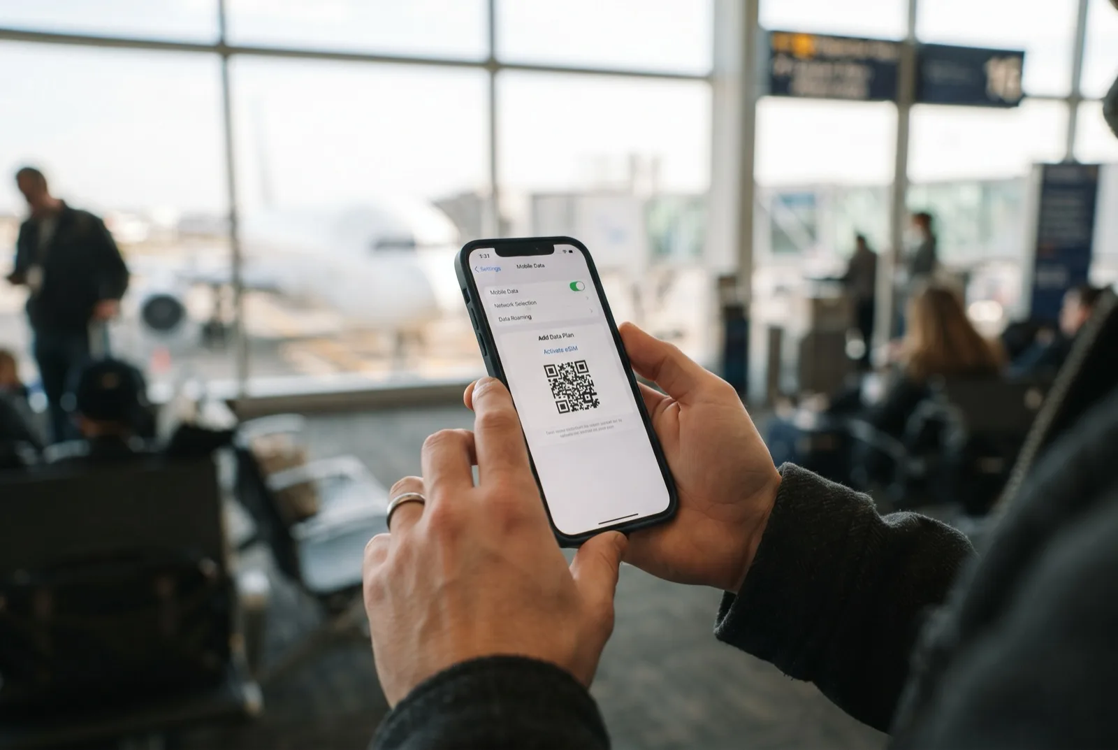 Smartphone mit eSIM-Einrichtung und QR-Code am Flughafen-Gate