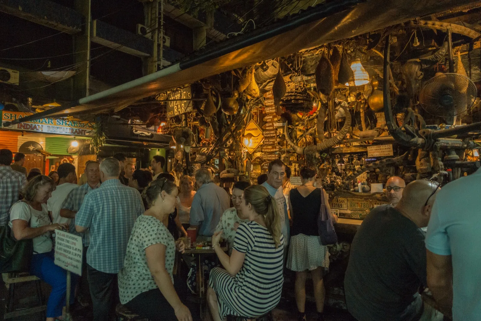 Urige lokale Bar in Bangkok mit schummrigem Licht und dicht gedrängten Gästen