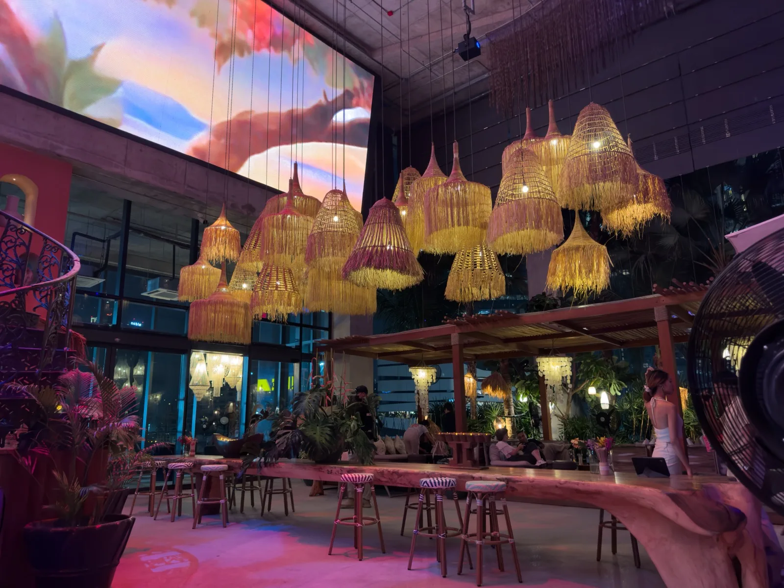 Moderne Design-Bar in Bangkok mit geflochtenen Lampenschirmen und großer LED-Wand