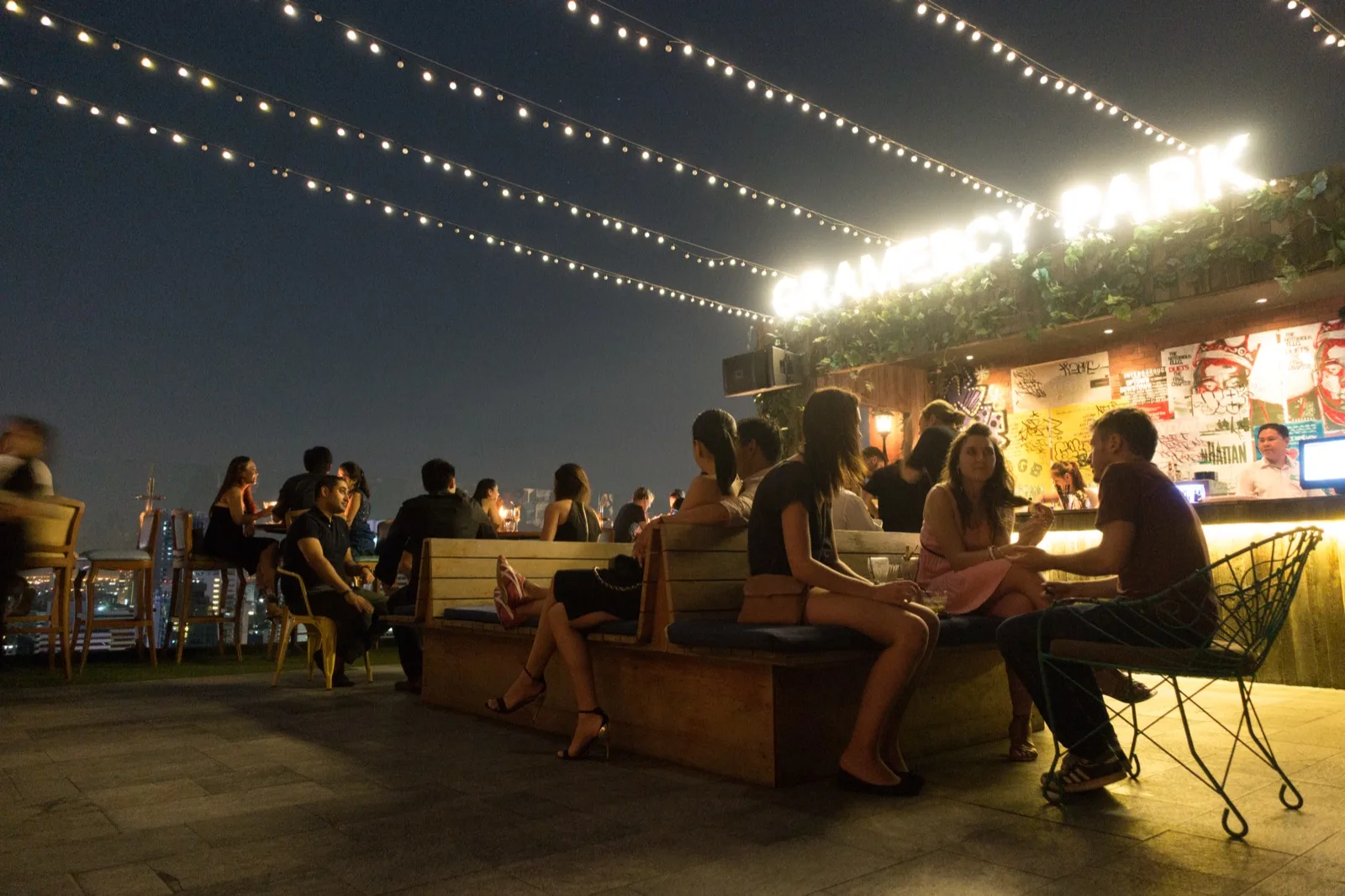 Entspannte Abendstimmung mit Gästen auf Holzbänken in einer Bar in Bangkok