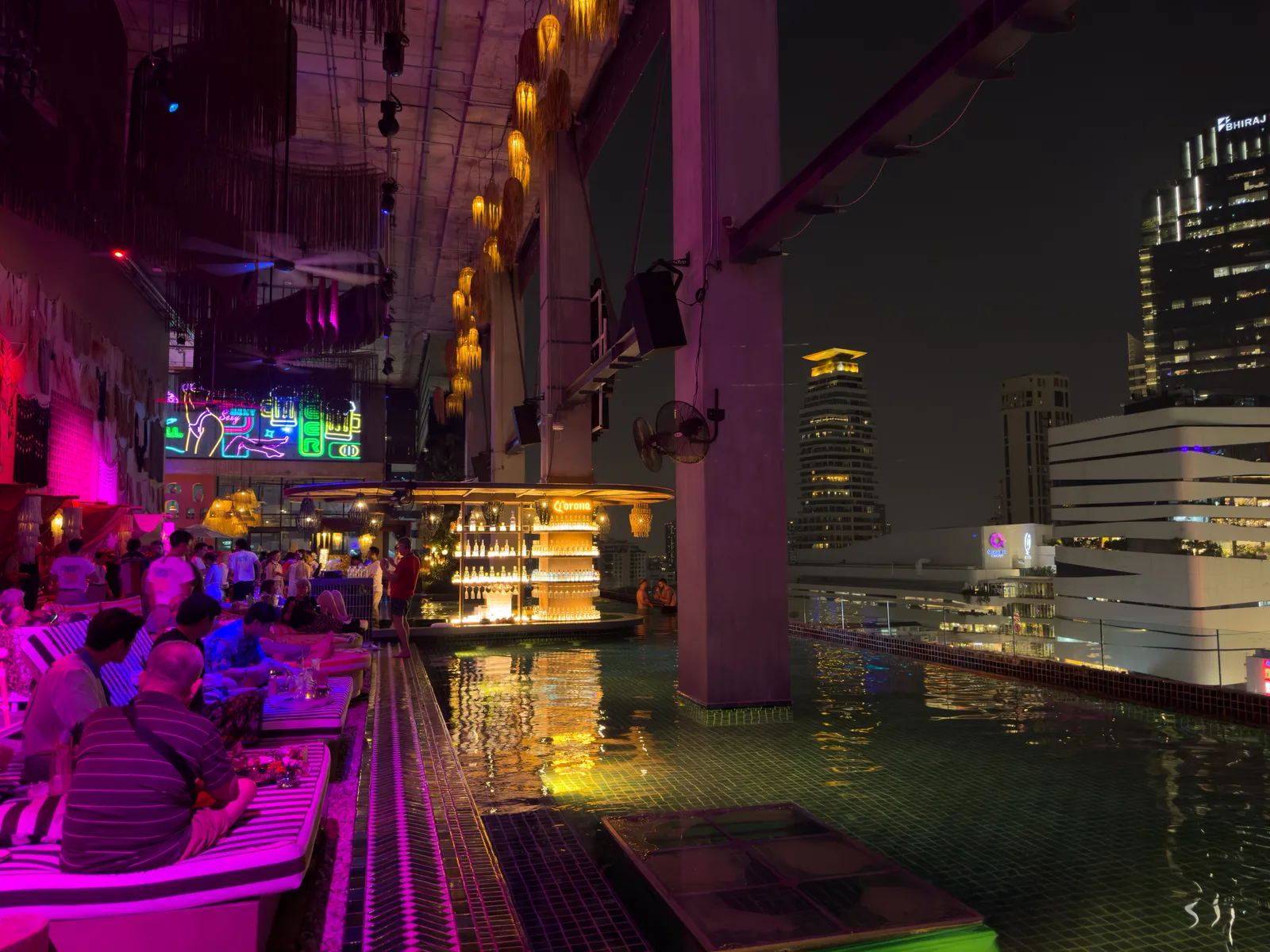 Rooftop-Bar mit Pool und Blick auf die beleuchtete Skyline von Bangkok bei Nacht