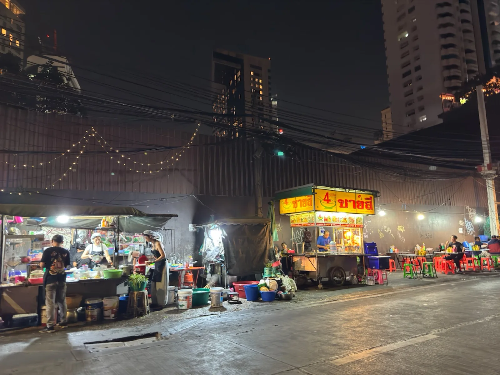 Streetfood-Stände mit Lichtern auf einem Nachtmarkt in Bangkok