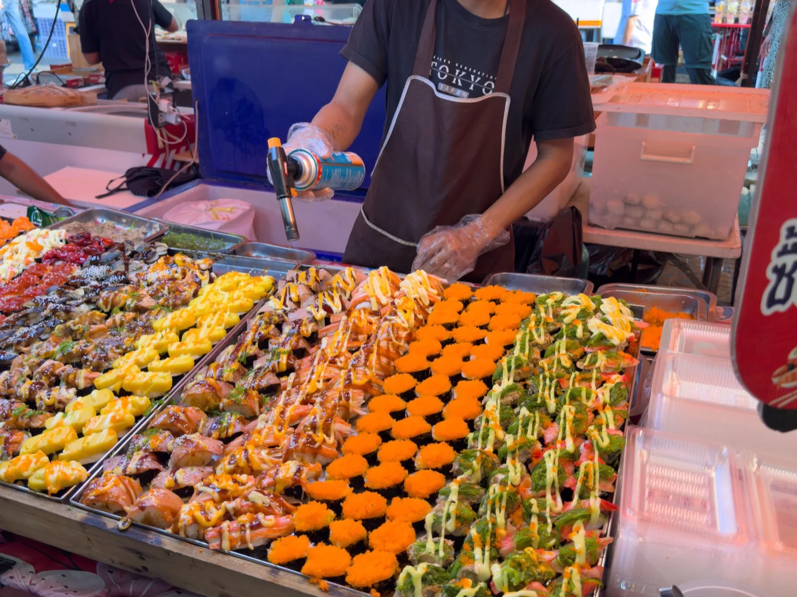Streetfood-Stand mit frisch zubereitetem Sushi auf einem Markt in Bangkok