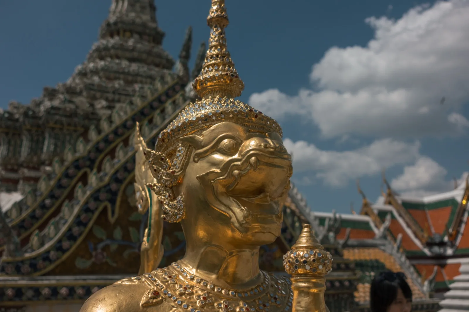 Goldene Kinnari-Statue vor Tempeldächern im Wat Phra Kaew in Bangkok