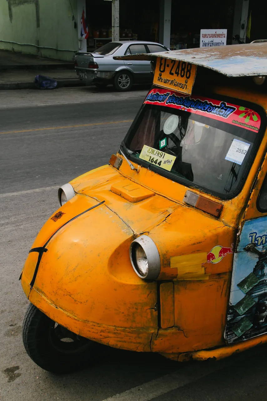 Orangefarbenes Tuk-Tuk im typischen Ayutthaya-Design am Straßenrand