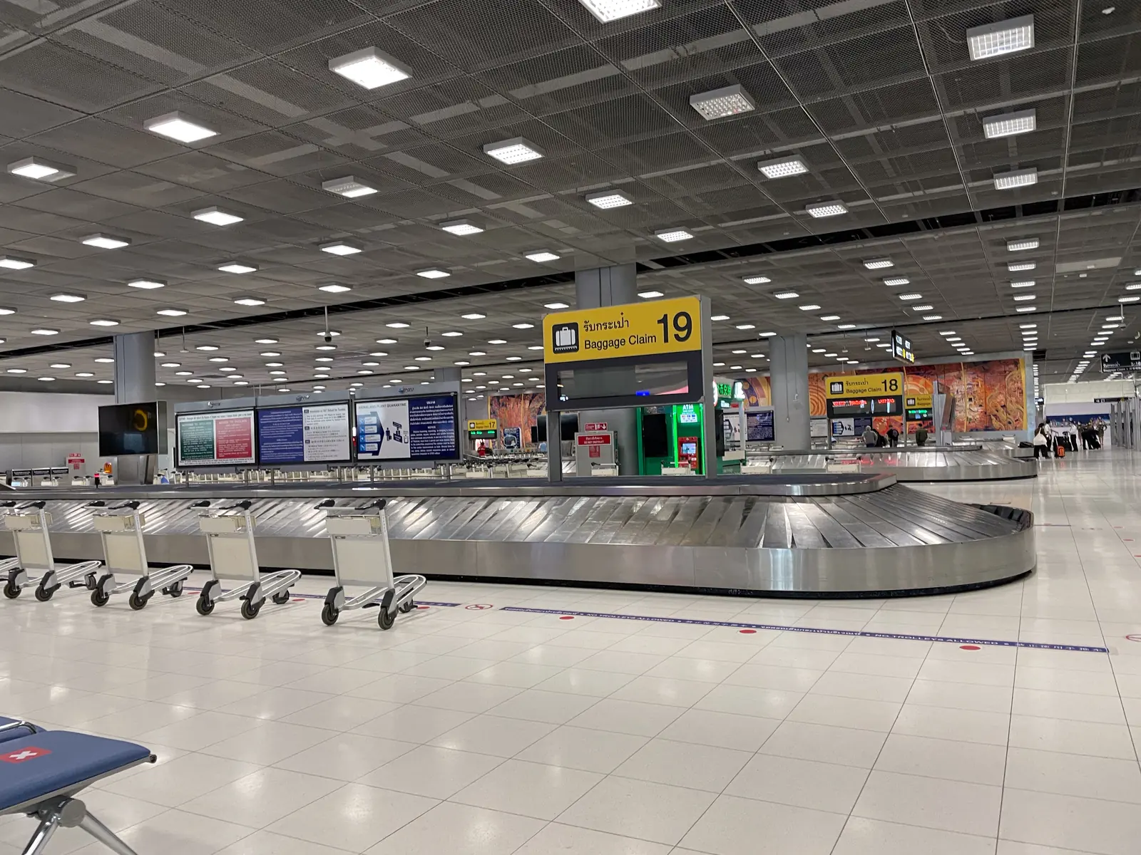 Gepäckband 19 in der Ankunftshalle des Flughafens Suvarnabhumi mit bereitstehenden Gepäckwagen